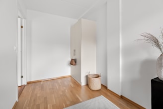 A white room with a wooden floor and a vase