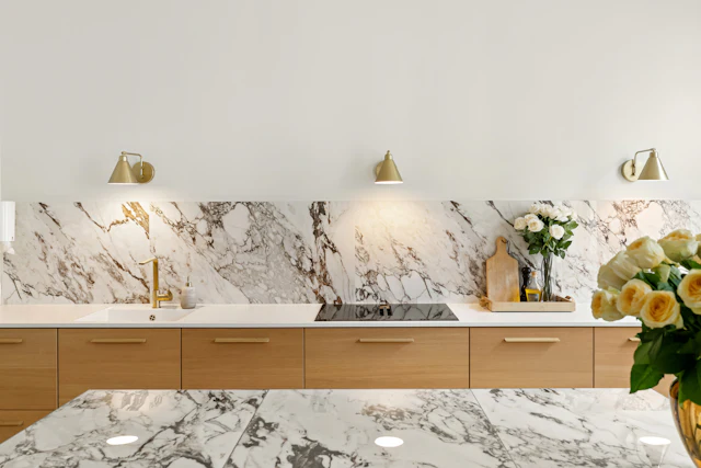 Bold-veined marble running from counter to wall with brass lamps and oak drawers