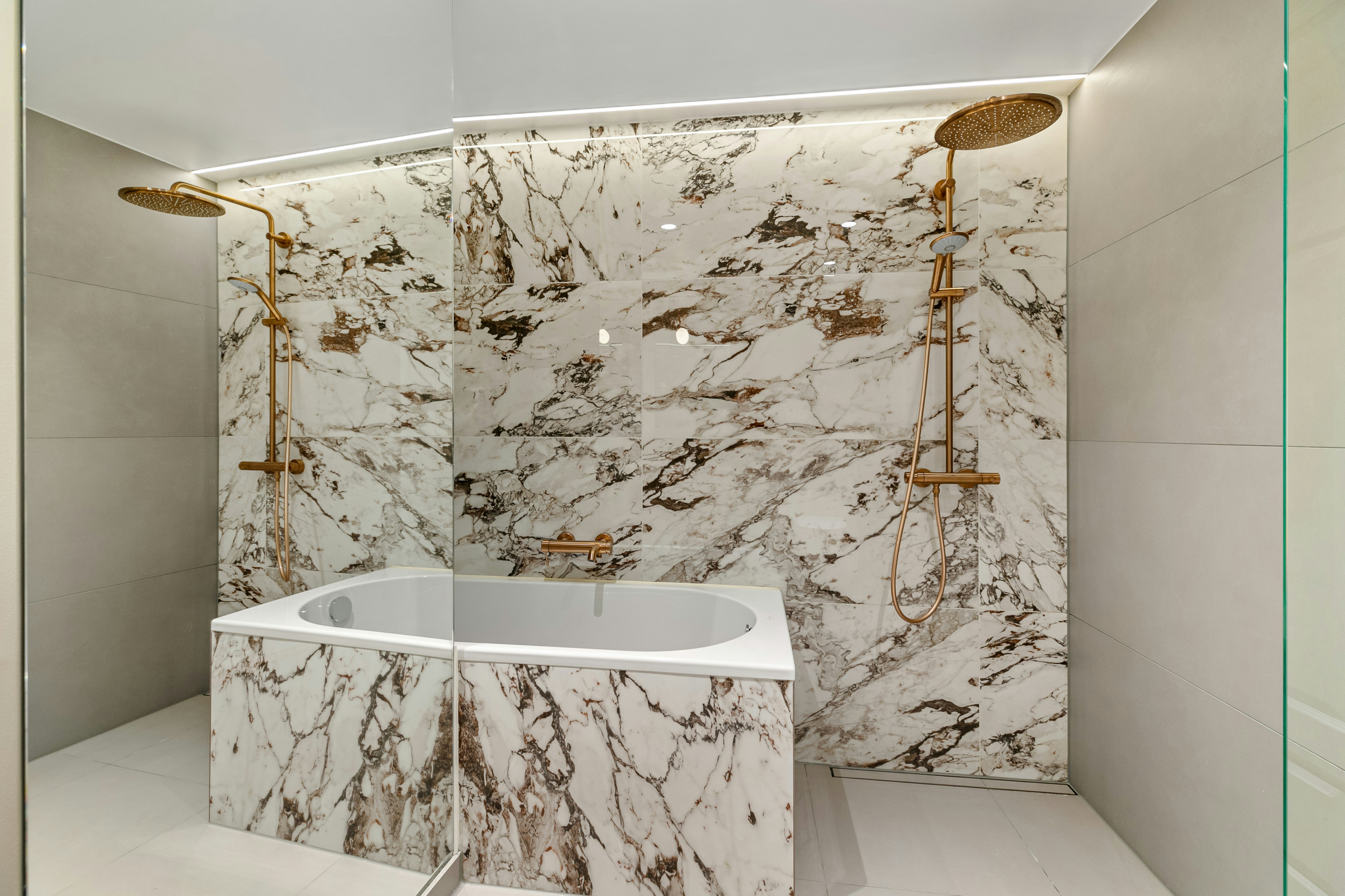 high-quality materials like a book-matched marble slab wall and custom vanity - high end bathroom remodel