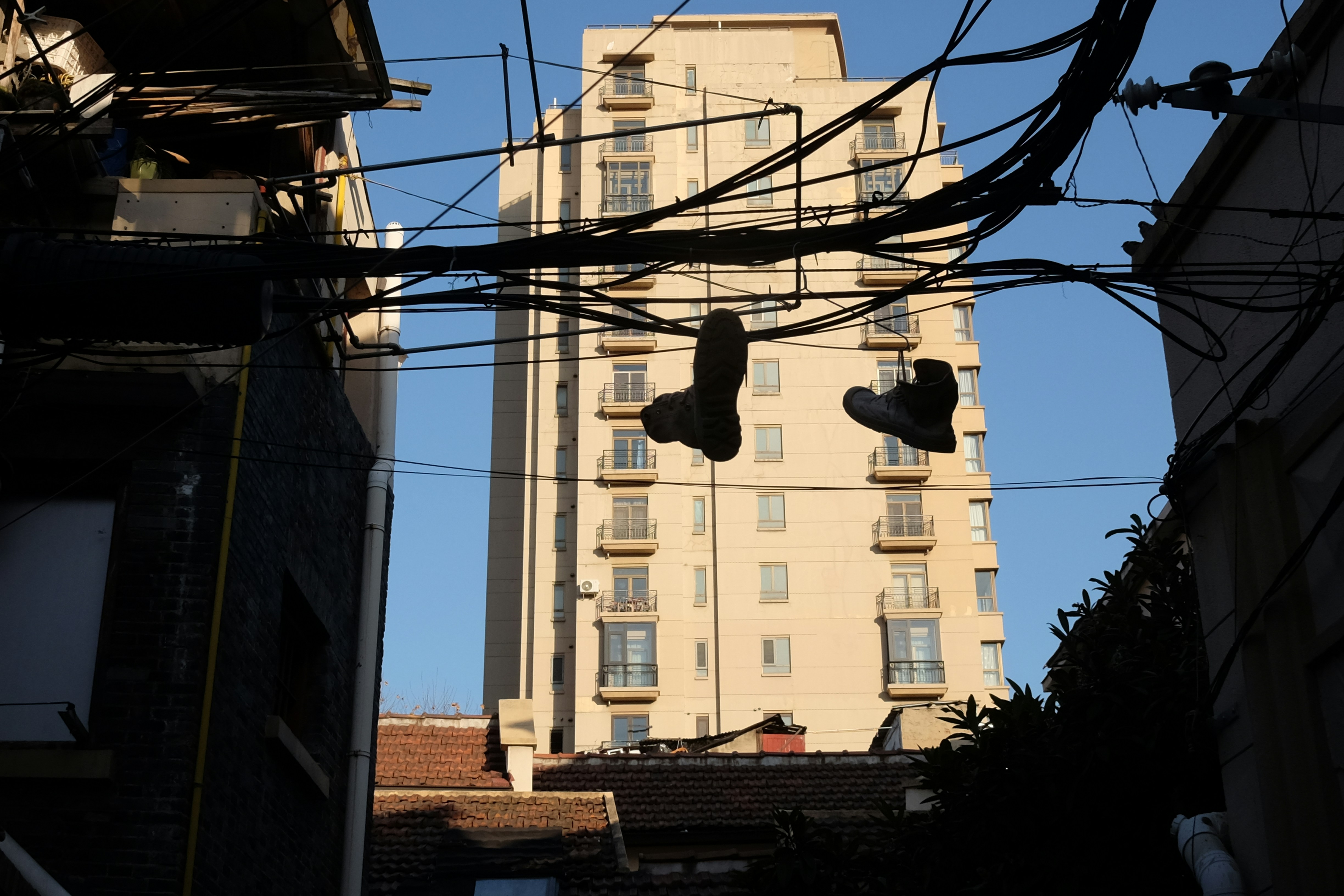 A pair of shoes hanging from a wire in front of a tall building