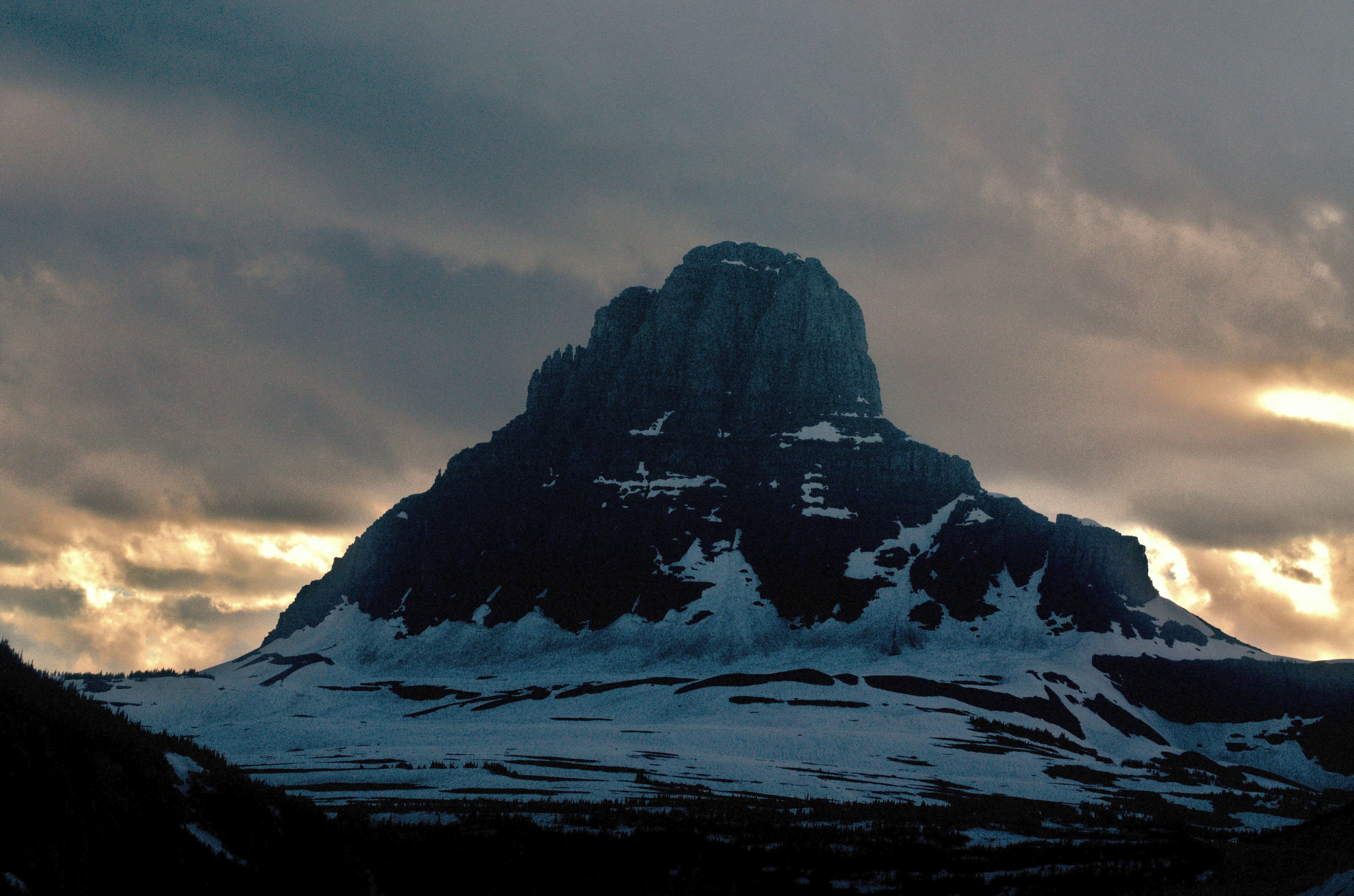 A snow covered mountain under a cloudy sky, 