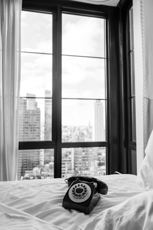 A black and white photo of a phone on a bed