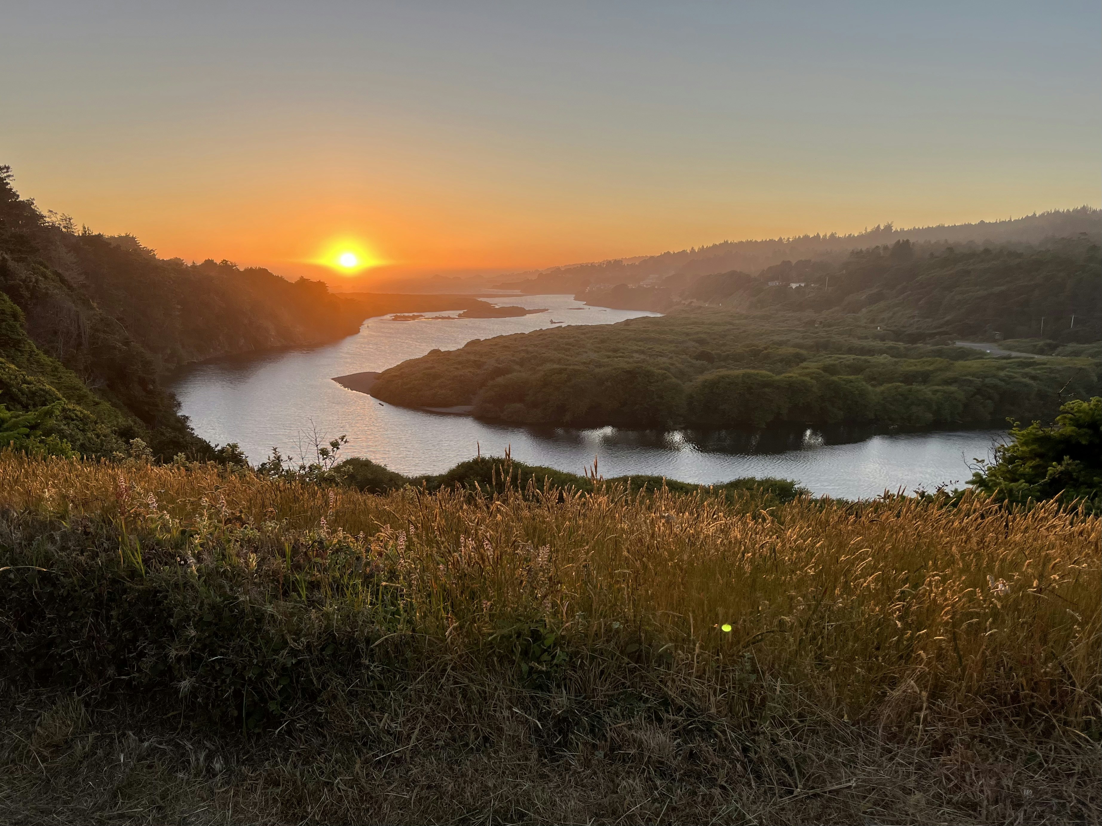 The sun is setting over a lake in the mountains