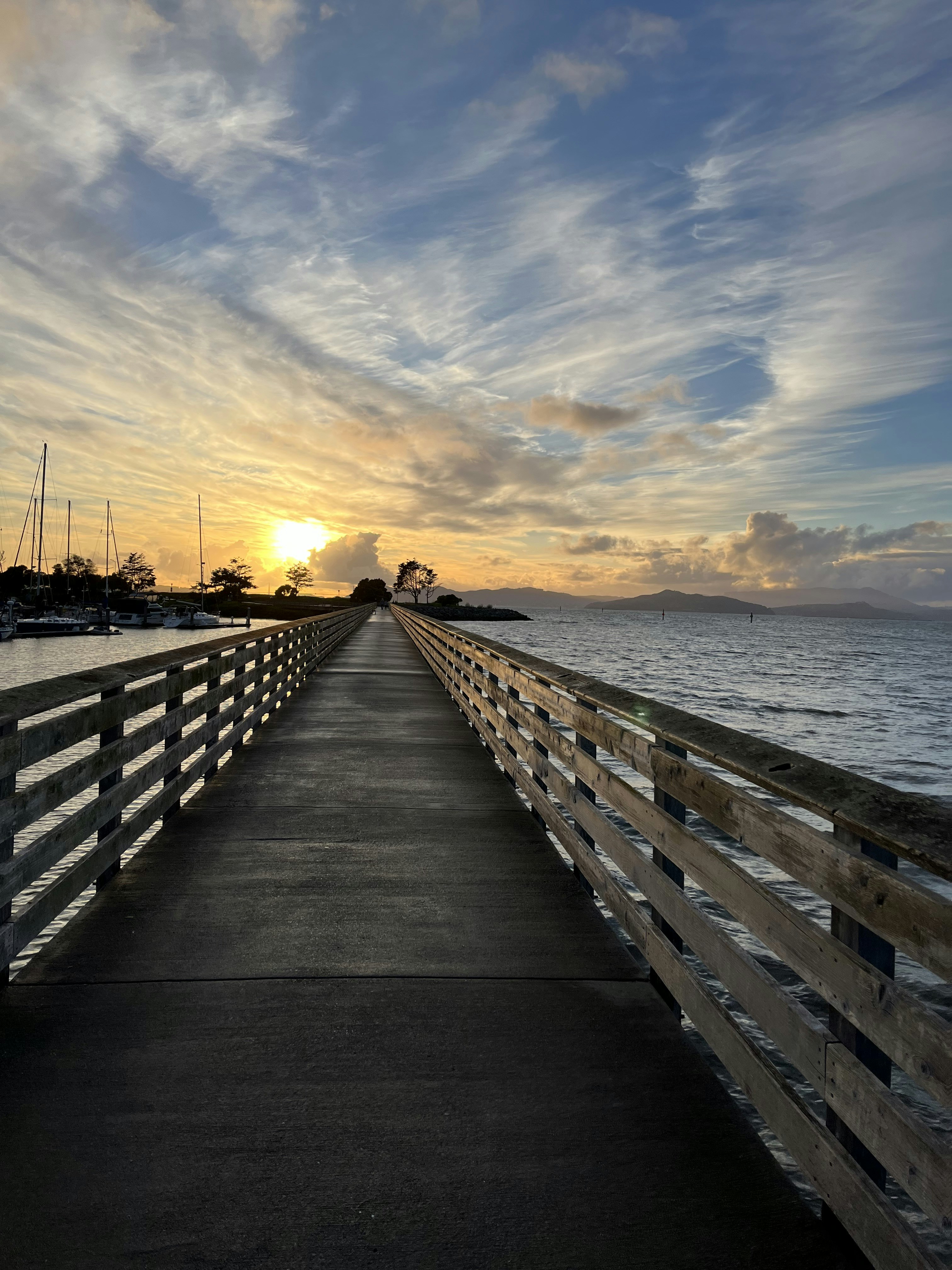 A long pier stretches out into the ocean as the sun sets