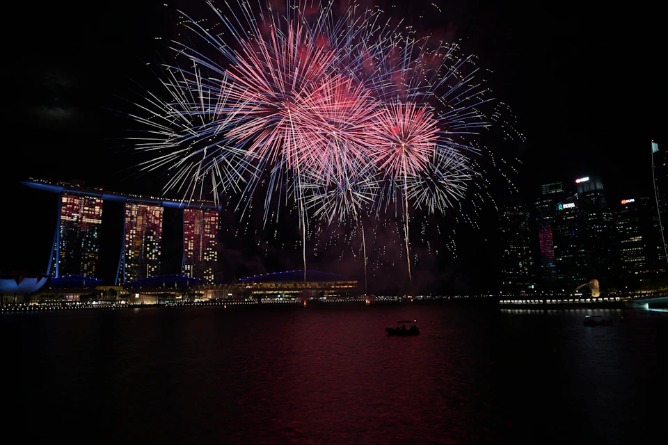 Fireworks bursting over Marina Bay at night, with Marina Bay Sands lit on the left