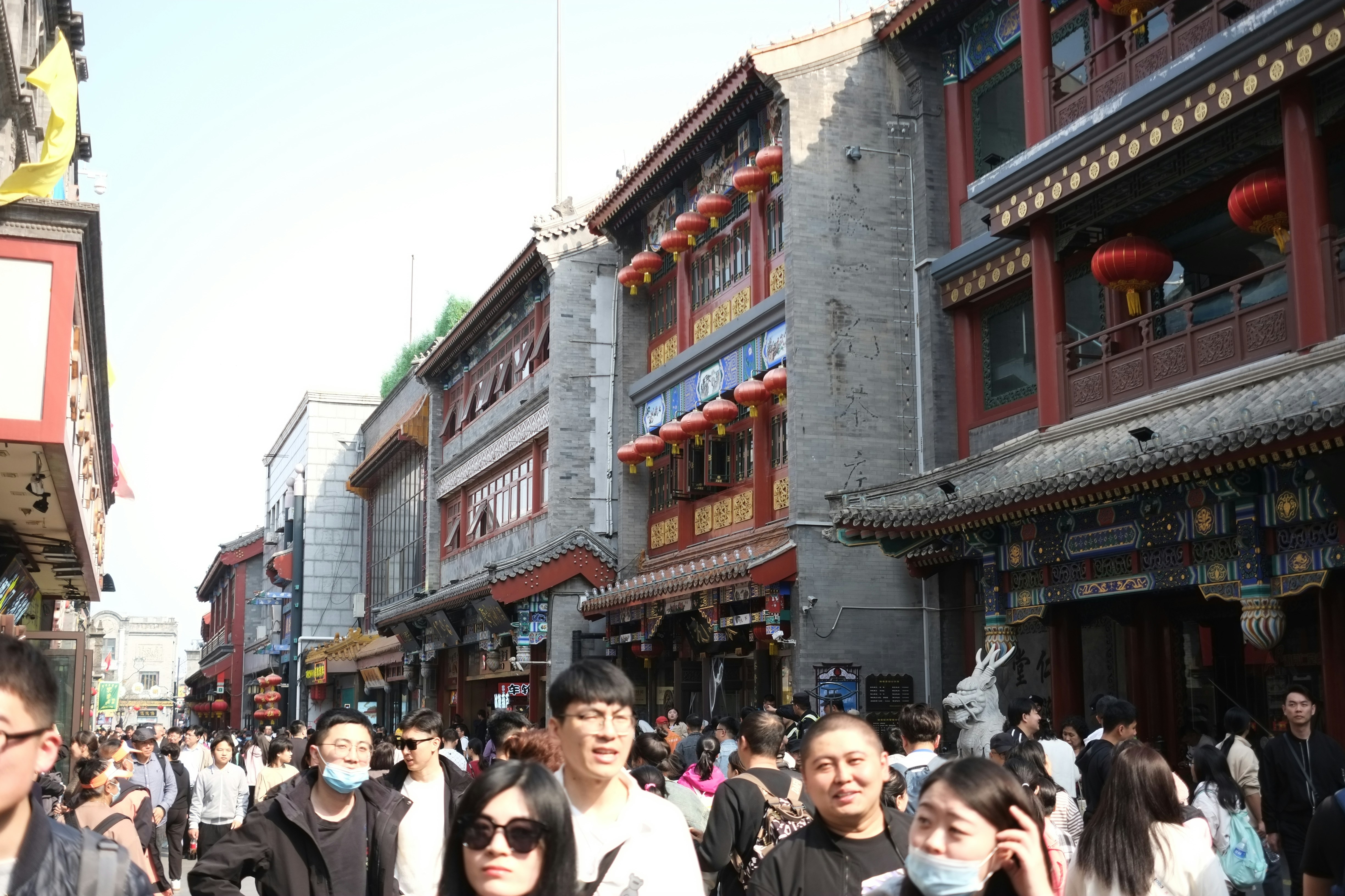 A group of people walking down a street next to tall buildings