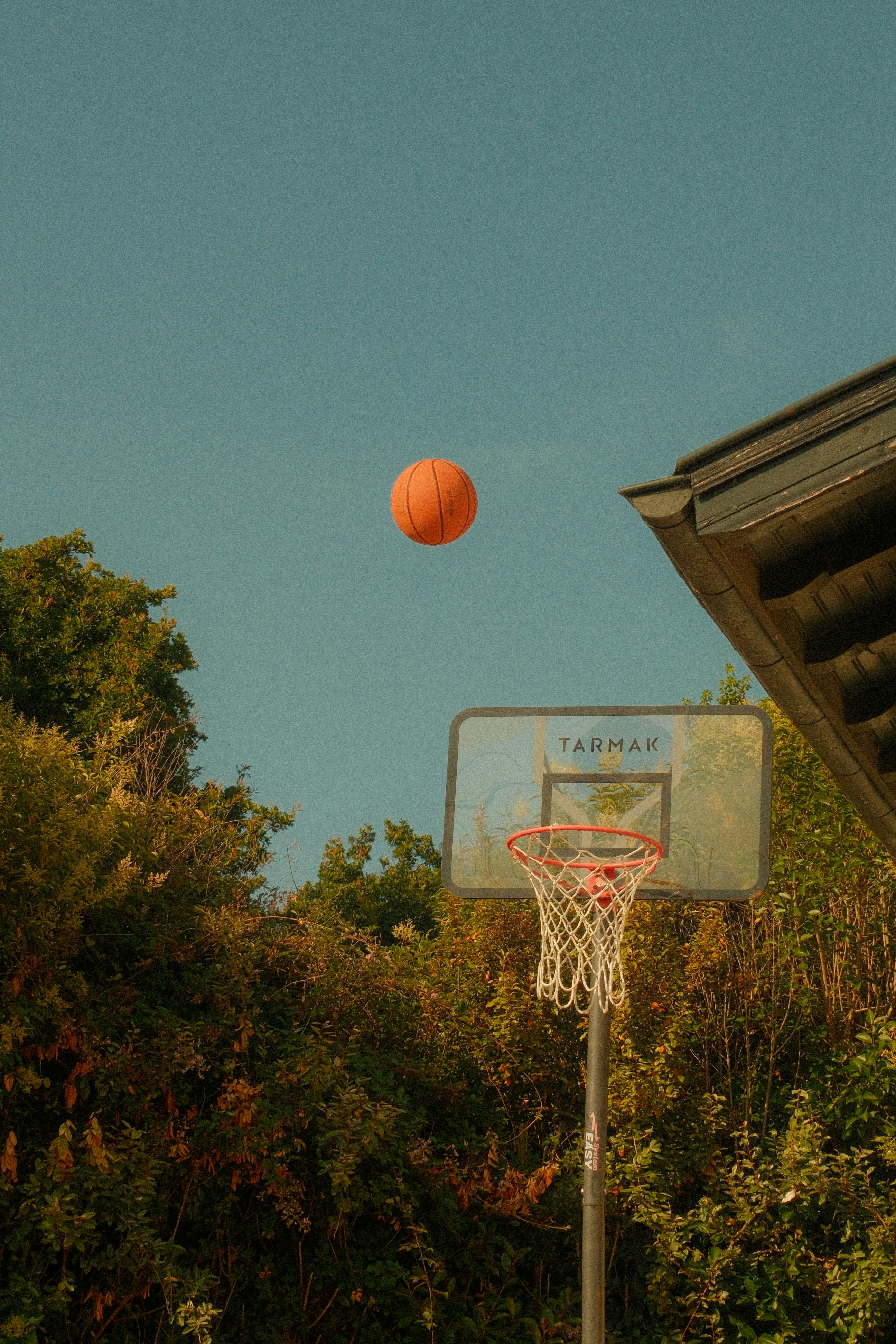 A basketball is in the air above a basketball hoop