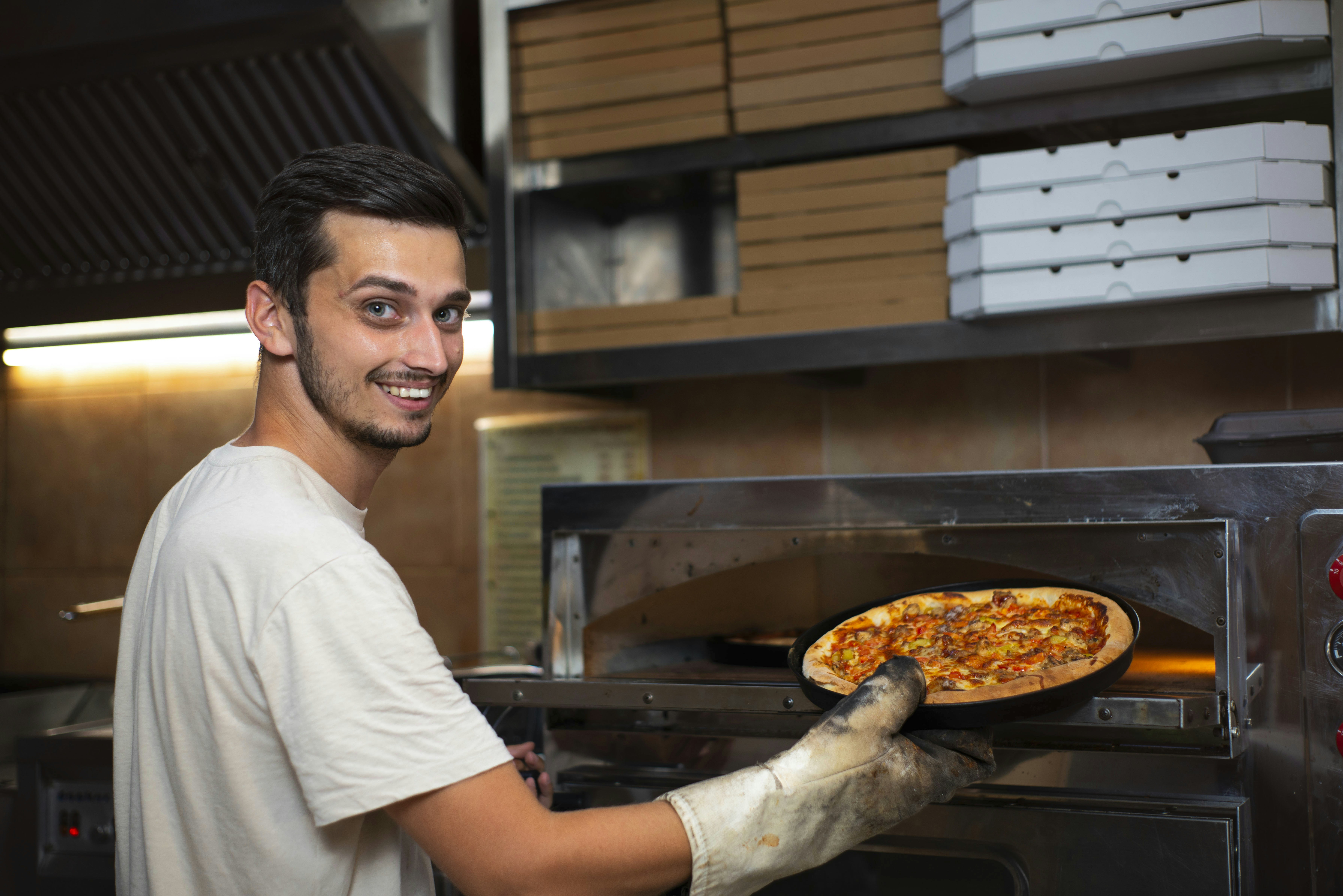 A man is taking a pizza out of the oven