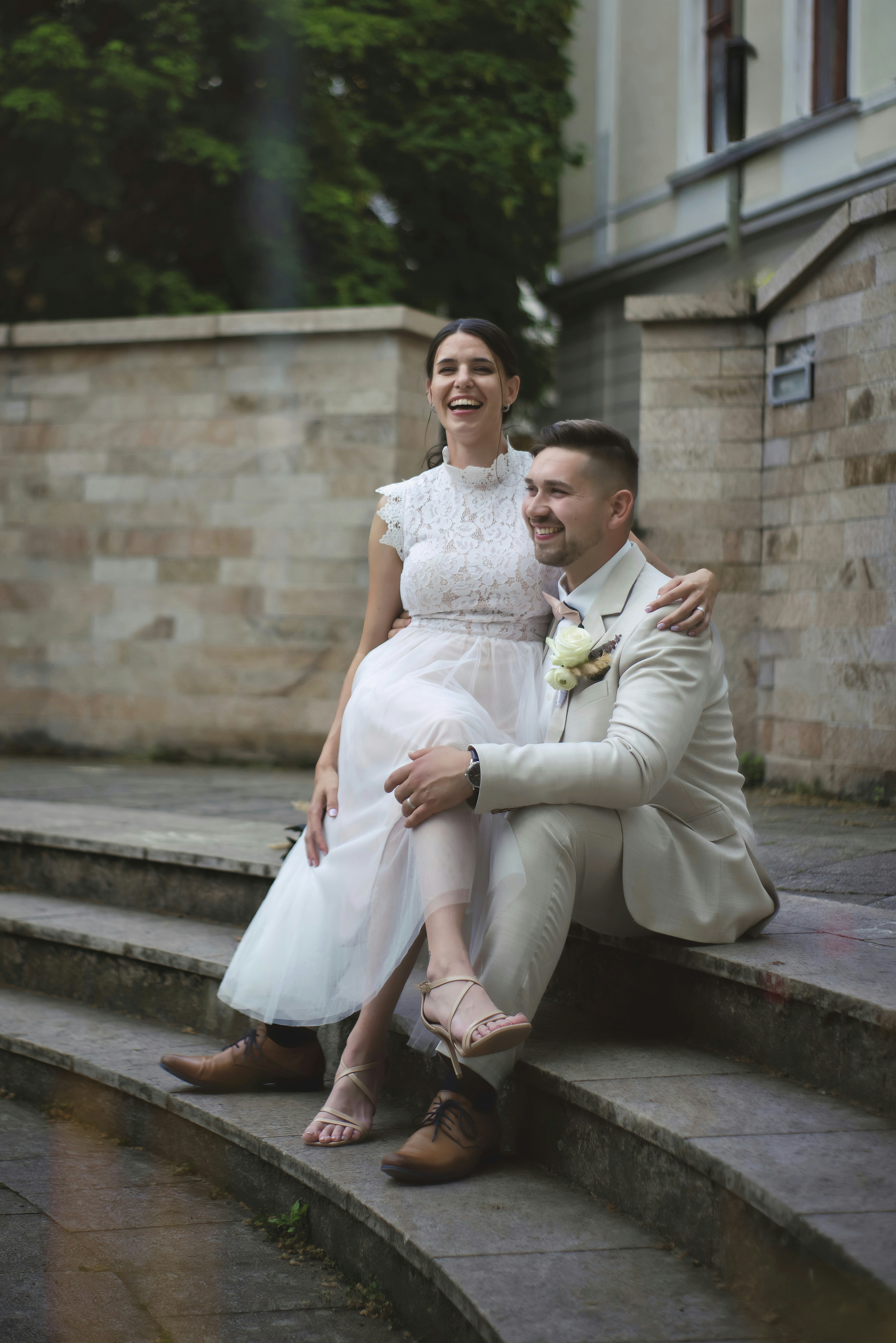 A bride and groom sitting on the steps of a building