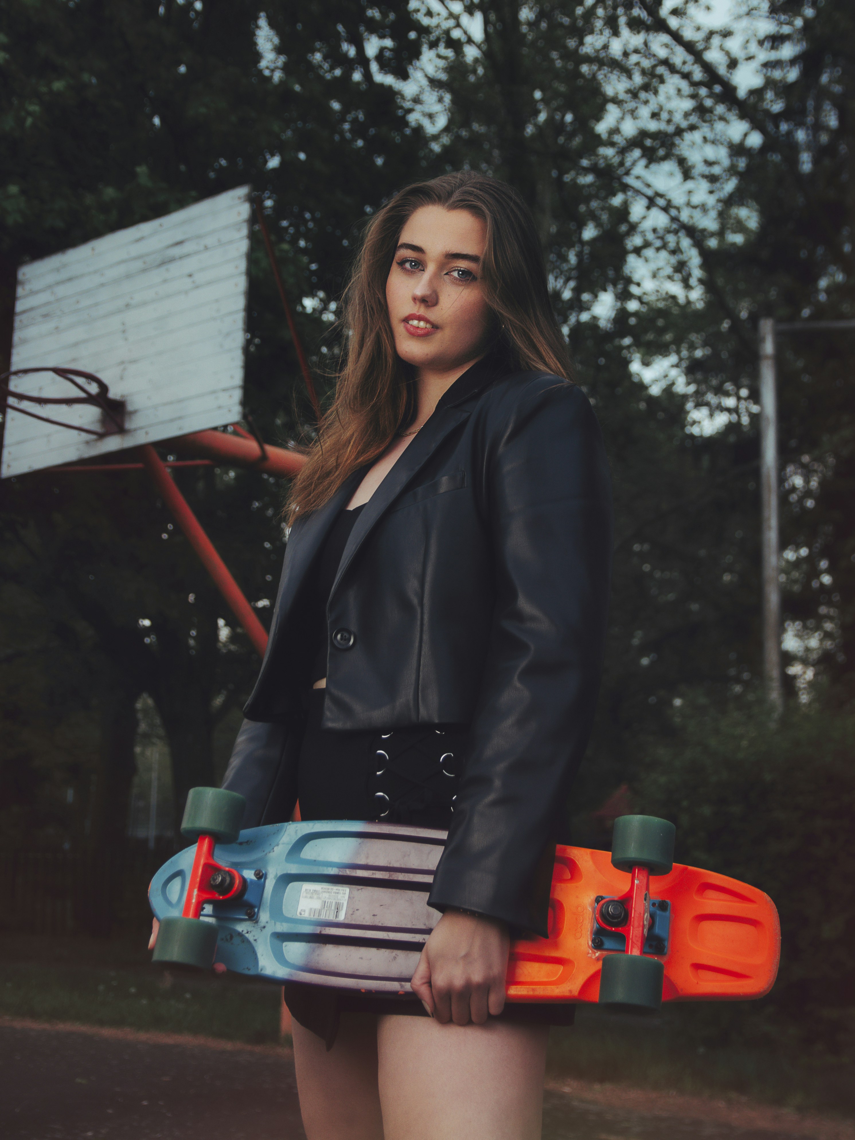 A woman holding a skateboard standing on a street