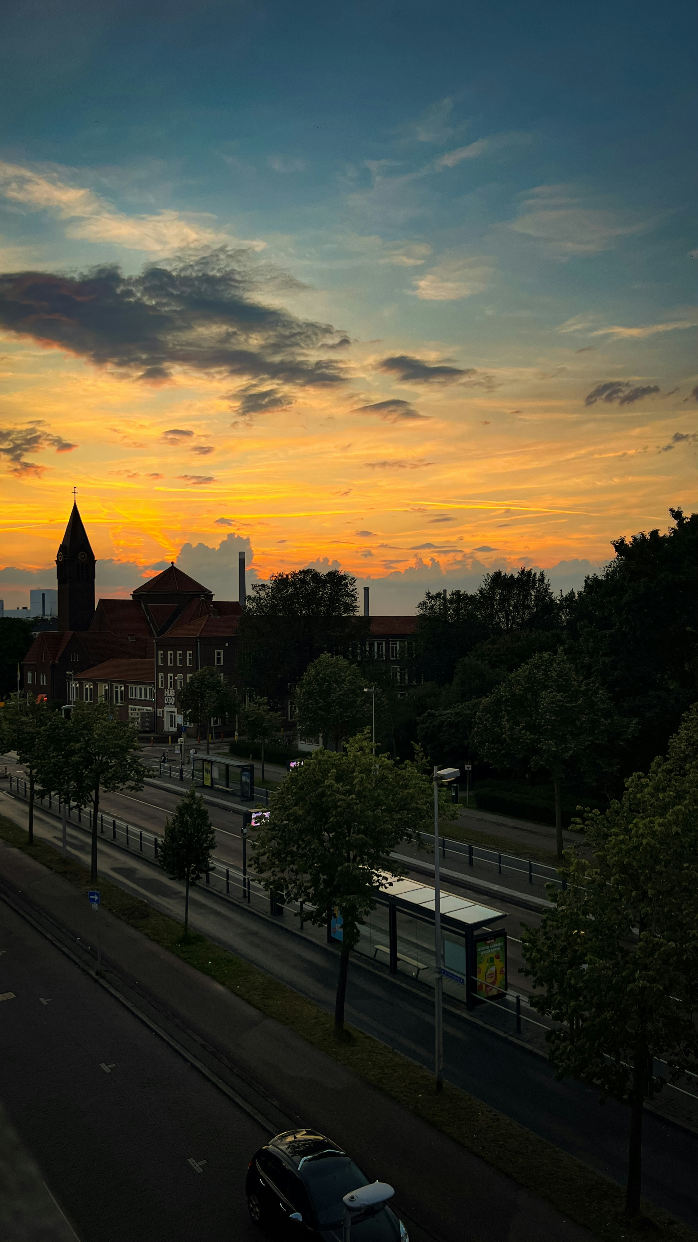 A sunset view of a city street with a clock tower in the distance