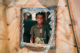 A young boy standing in a window of a structure