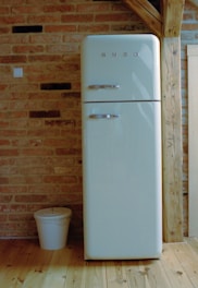 A white refrigerator freezer sitting on top of a wooden floor
