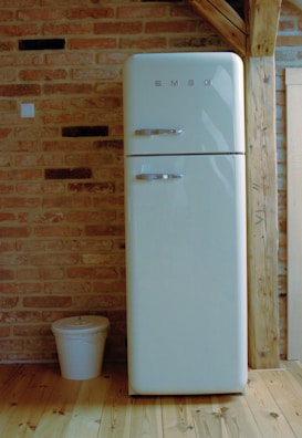 A white refrigerator freezer sitting on top of a wooden floor