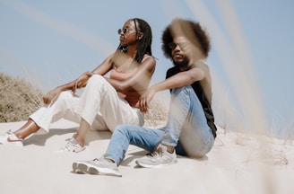 A couple of people sitting on top of a sandy beach
