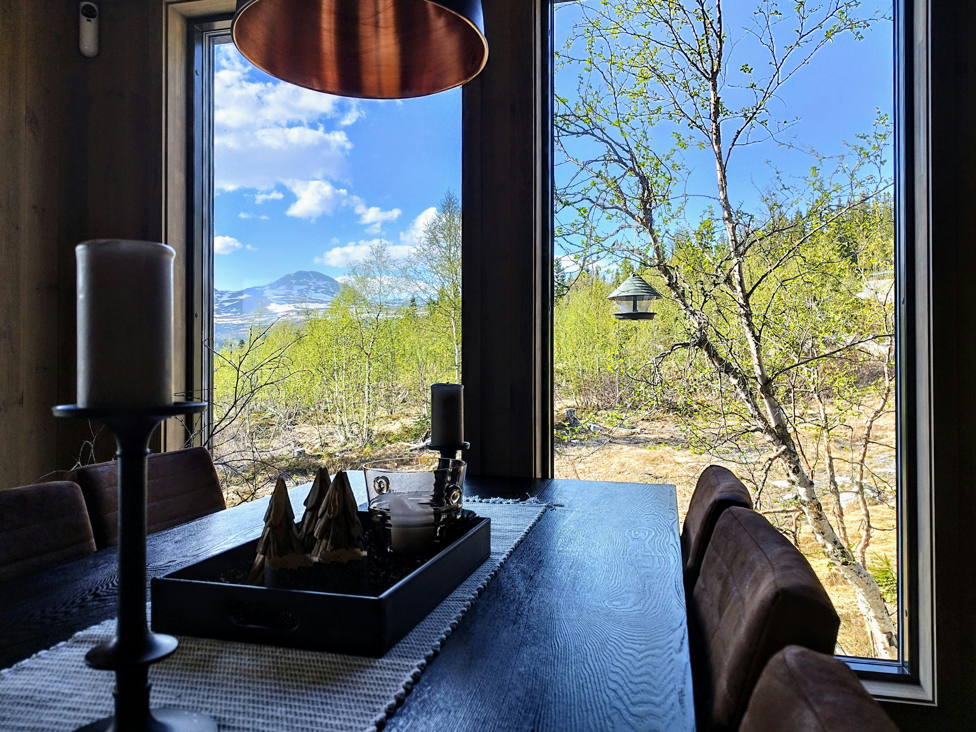 Dessert course being served at a candlelit table in the dining car with mountain scenery visible through the window at dusk