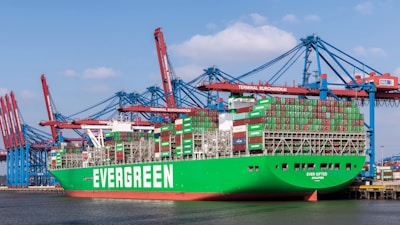 A large green cargo ship docked at a dock