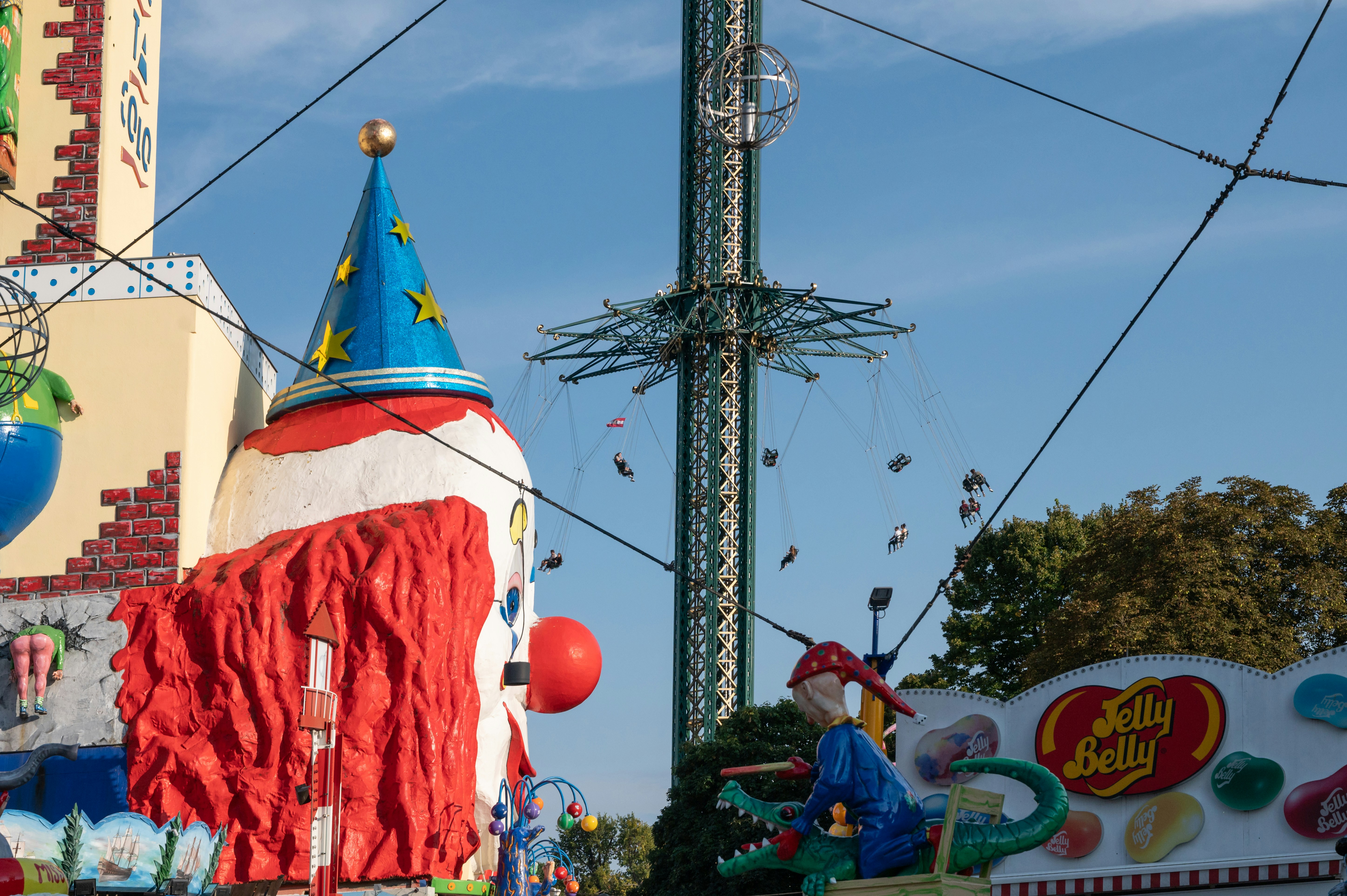 A carnival ride with a large red and white building in the background