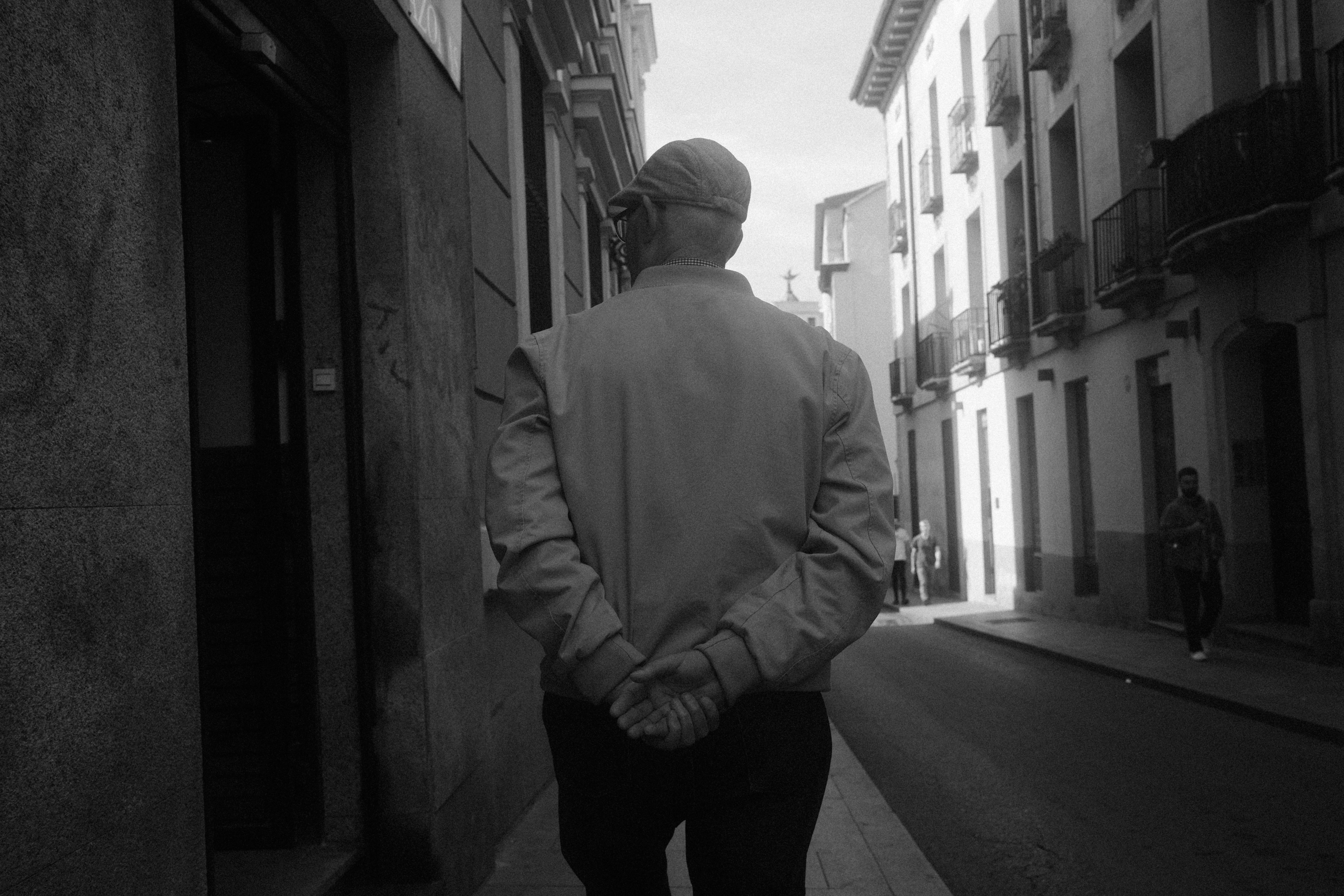 A man walking down a street next to tall buildings