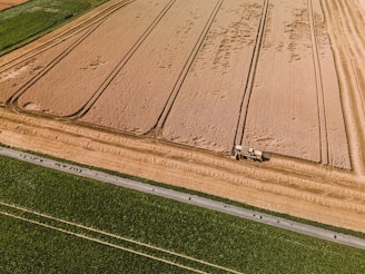 An aerial view of a farm field with a tractor in the middle of it