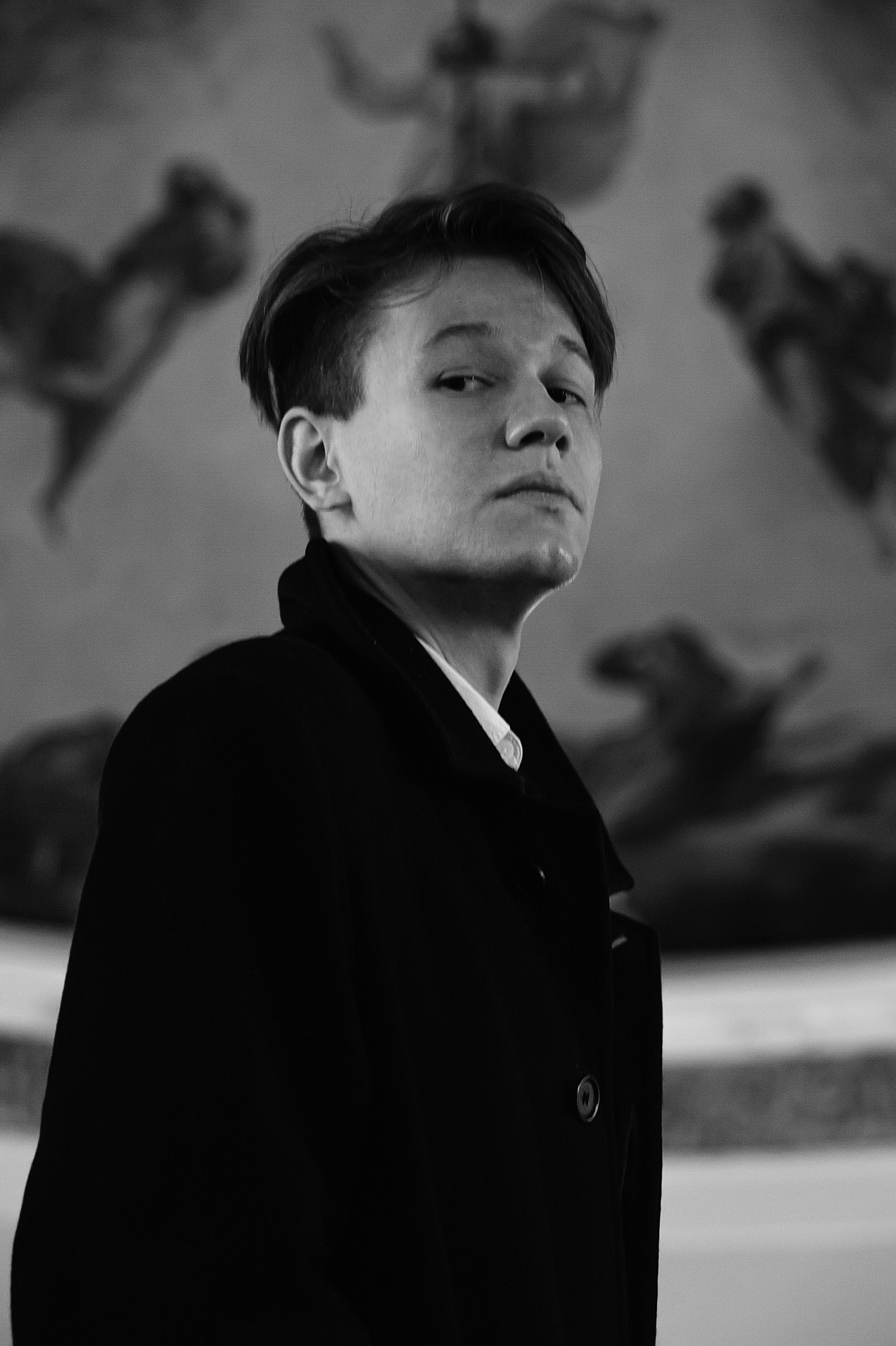 A black and white photo of a man standing in front of a painting
