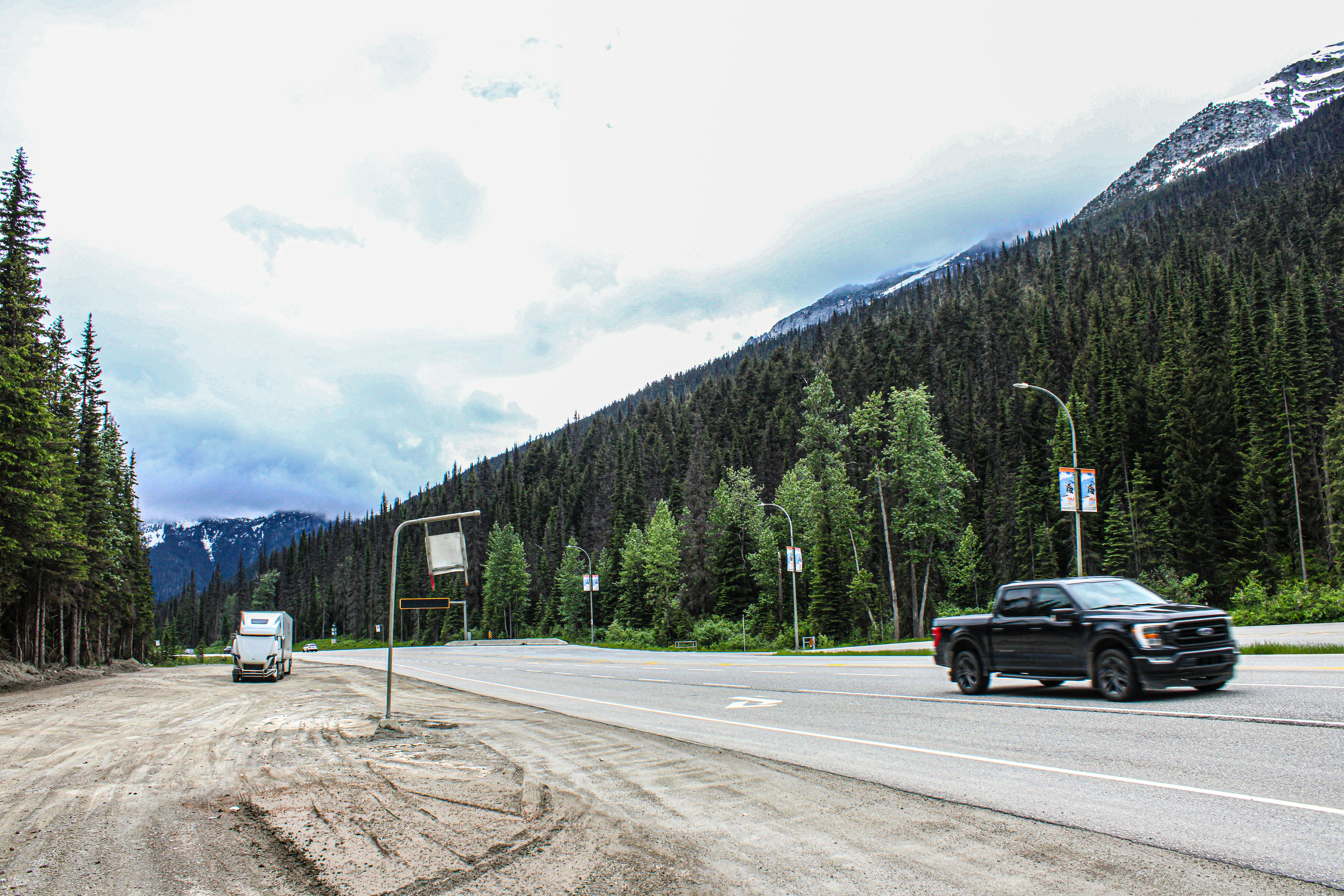 electric pickup truck charging highway - A car driving down a dirt road next to a forest