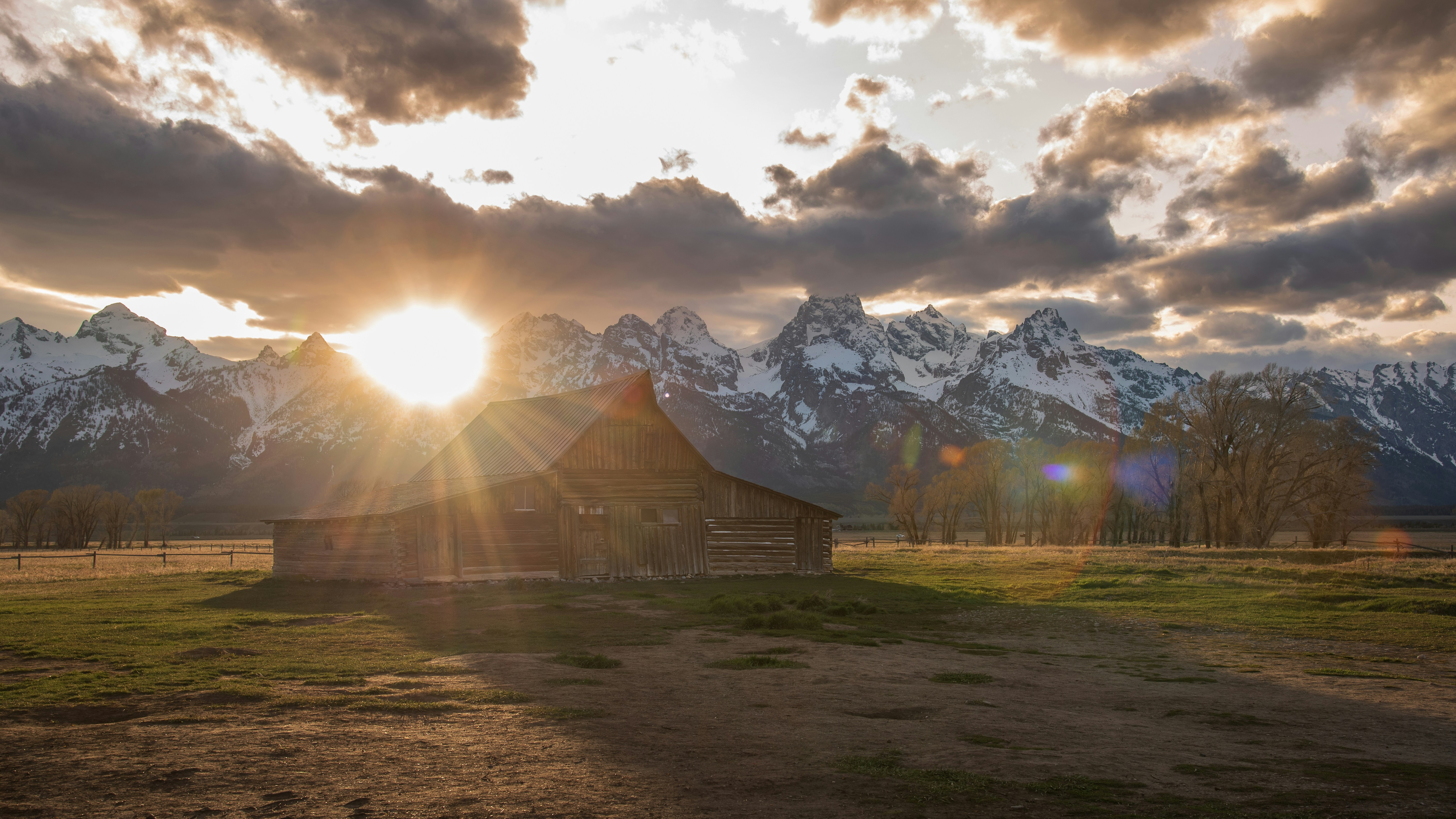 O sol está se pondo sobre um celeiro nas montanhas