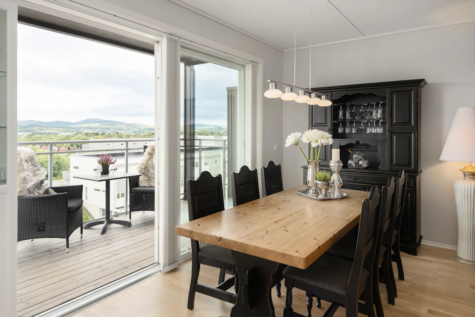 Large wooden table surrounded by six black chairs with white vases and fresh flowers