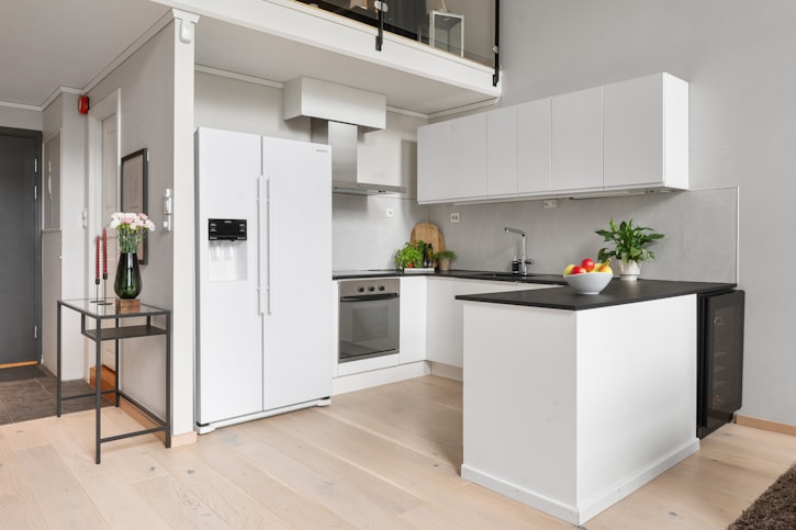 A kitchen with white cabinets and black counter tops