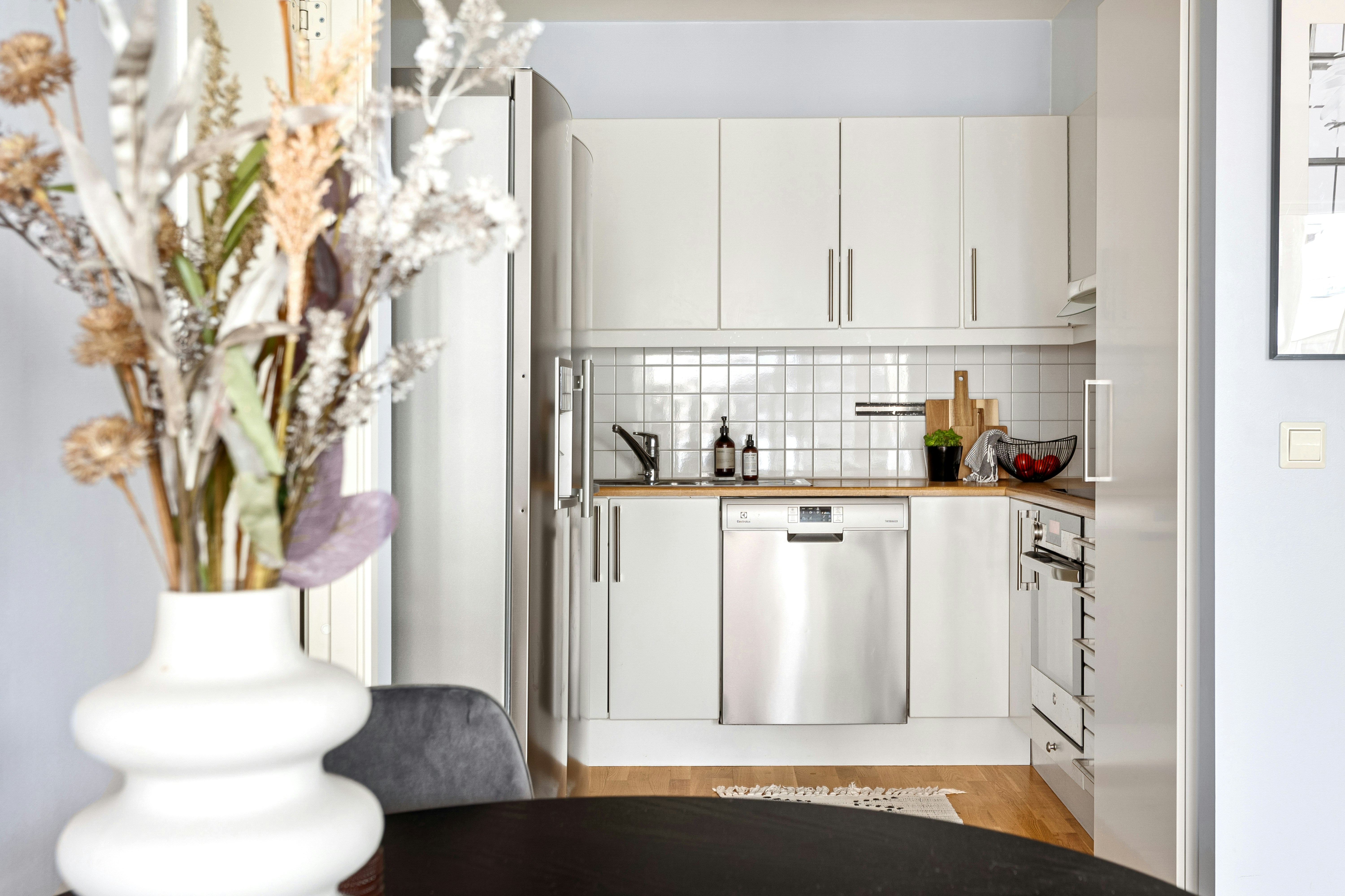 Bright clean white kitchen interior with sunlight, fresh flowers, and spotless countertops