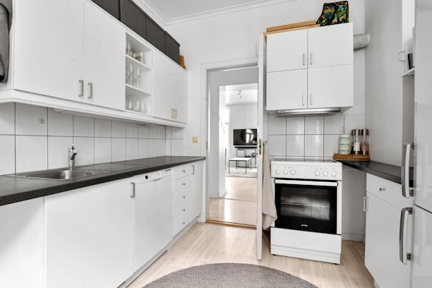A kitchen with white cabinets and black counter tops