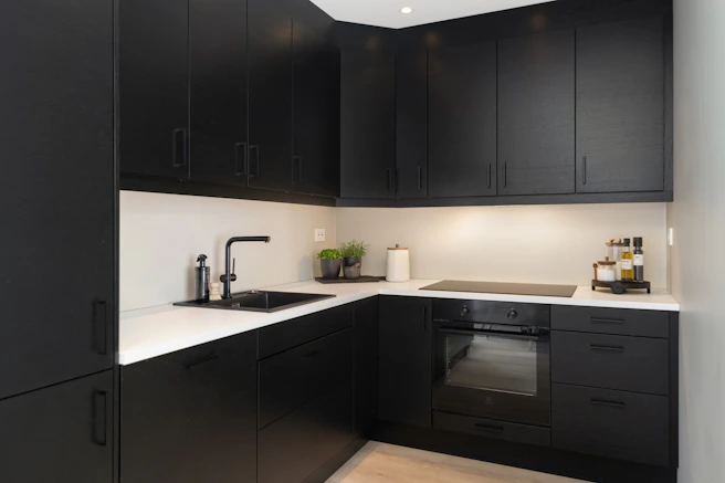 A kitchen with black cabinets and white counter tops