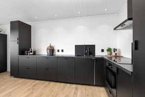 A kitchen with black cabinets and a wooden floor