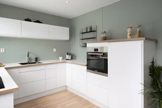 A kitchen with white cabinets and a wooden floor
