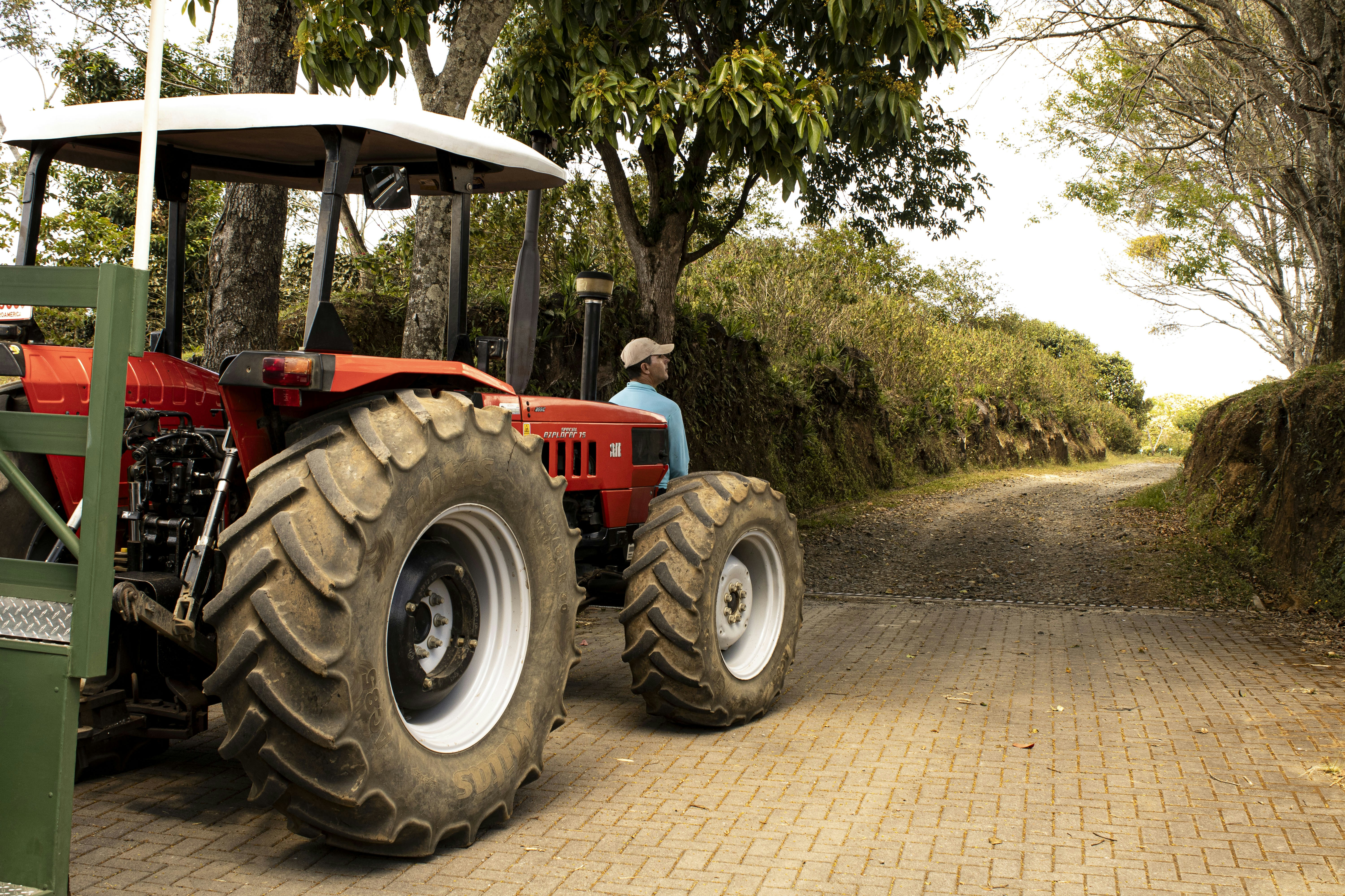 A man driving a tractor down a dirt road