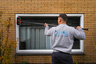 A man holding a baseball bat in front of a window