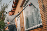 A man holding a large metal pole in front of a house