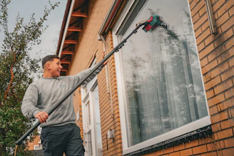 A man holding a large metal pole in front of a house