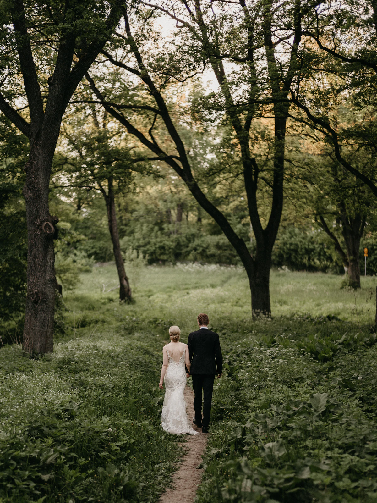 A bride and groom walking away through a wooded setting