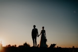 A bride and groom holding hands at sunset