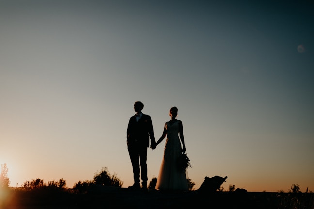 A bride and groom holding hands at sunset