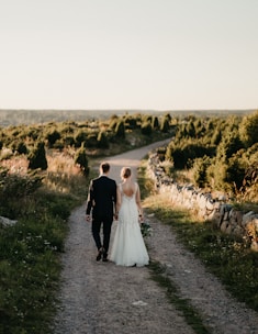 A bride and groom walking down a dirt road