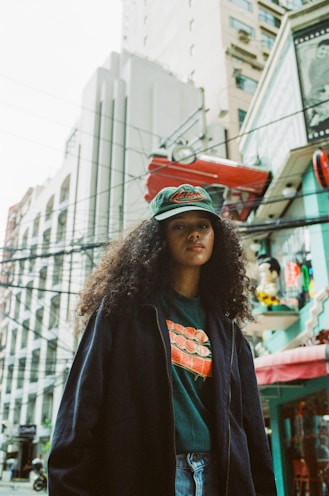 A woman standing on a city street with a skateboard on her head