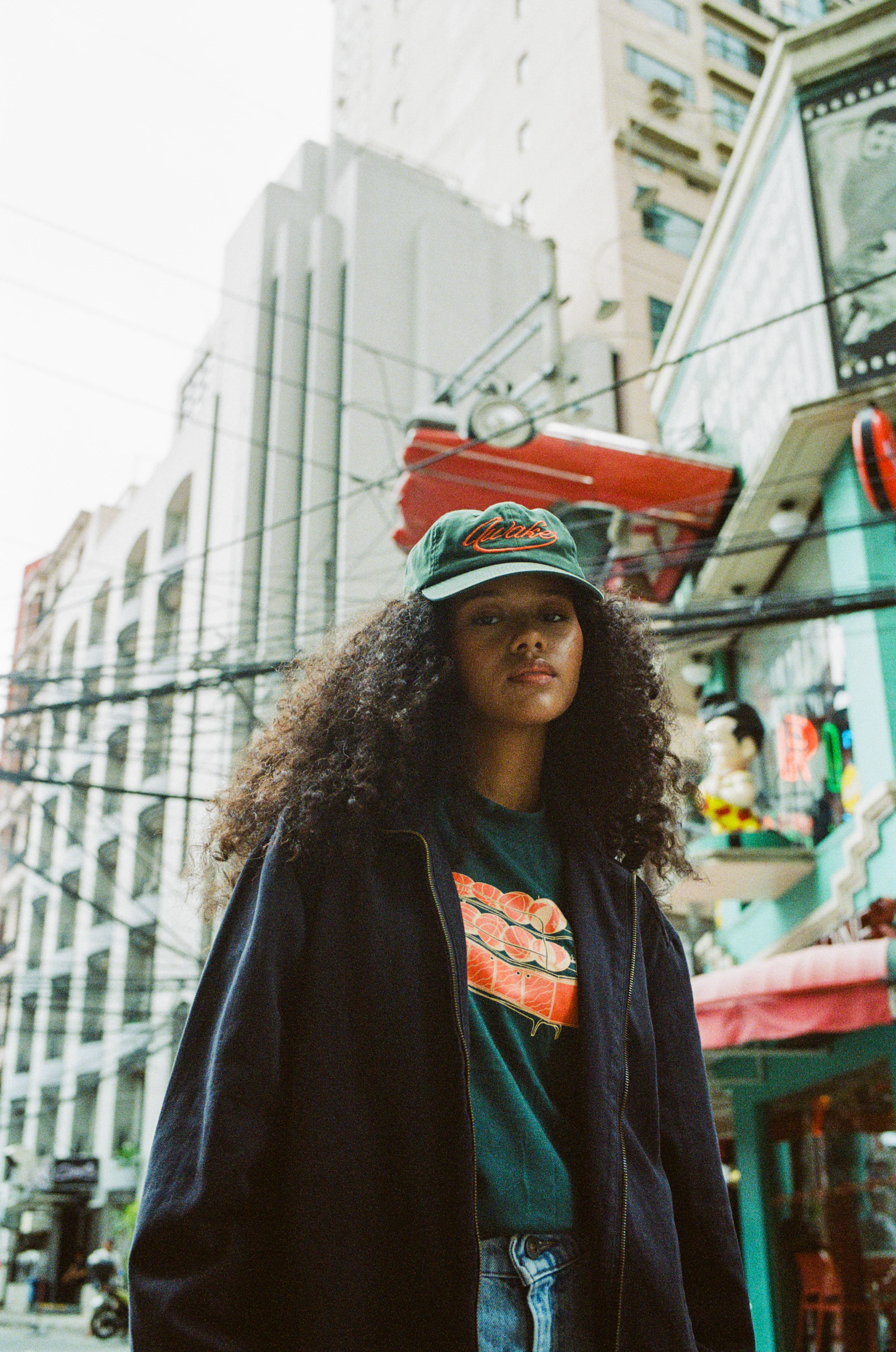 Woman in a black jacket riding a skateboard on a city street, editorial fashion shot