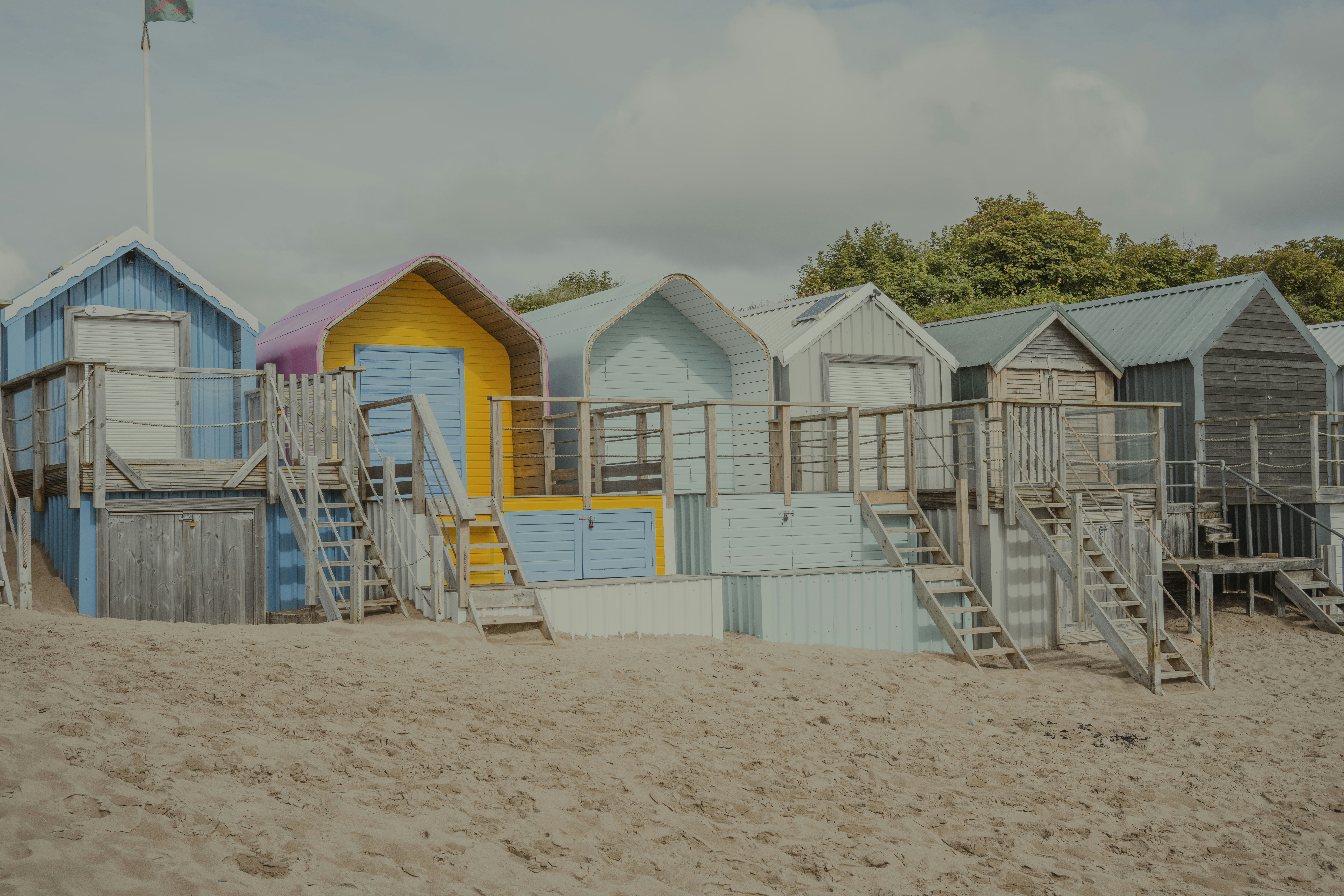 A row of beach huts sitting on top of a sandy beach