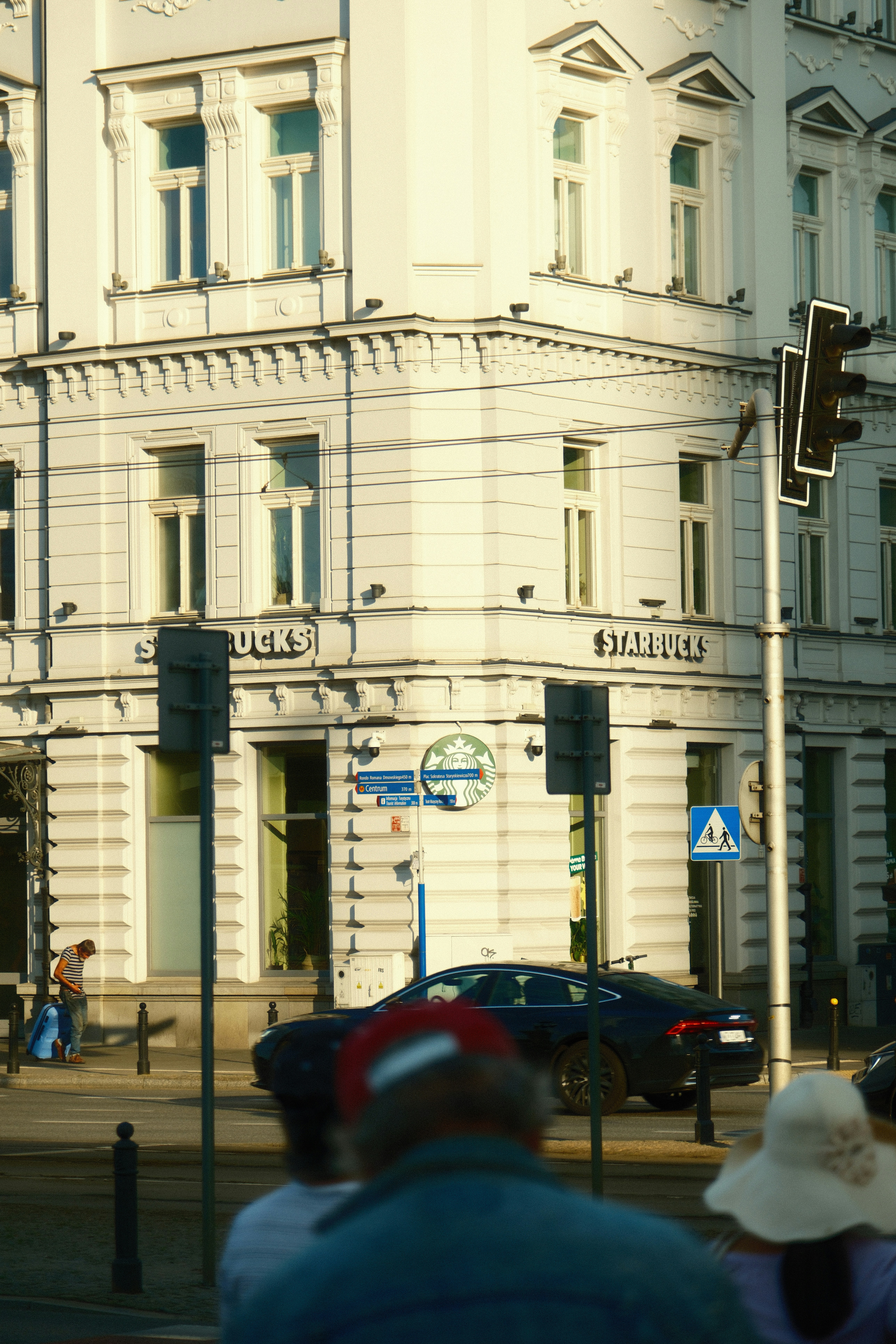 A group of people walking down a street next to a tall white building