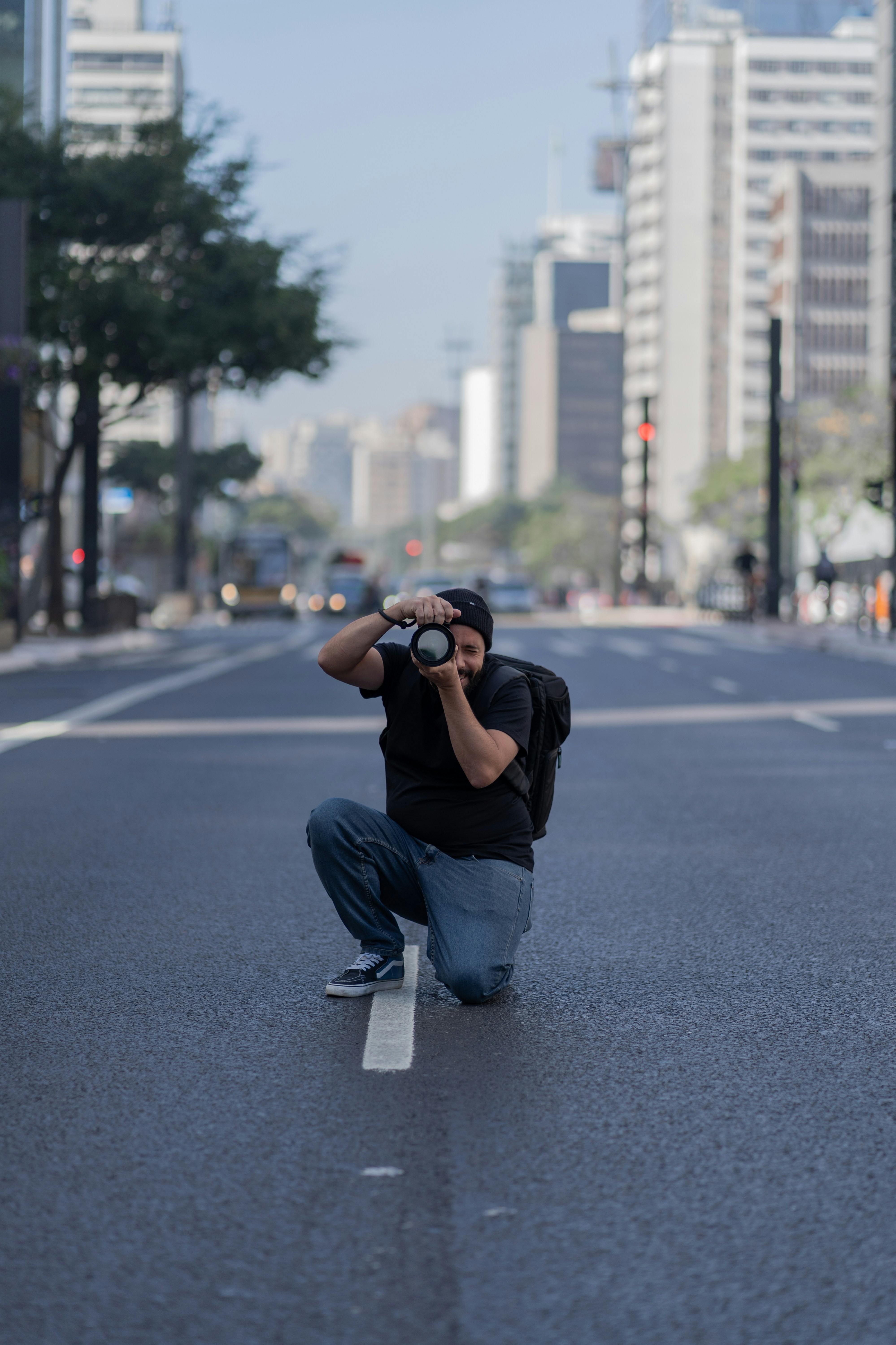 A man kneeling down on the side of a road taking a picture