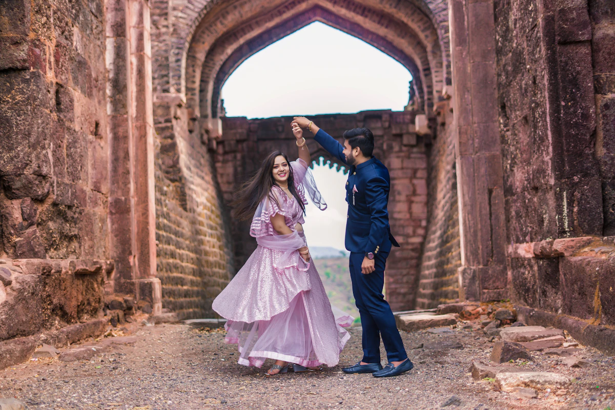 A man twirling a woman in front of a stone archway