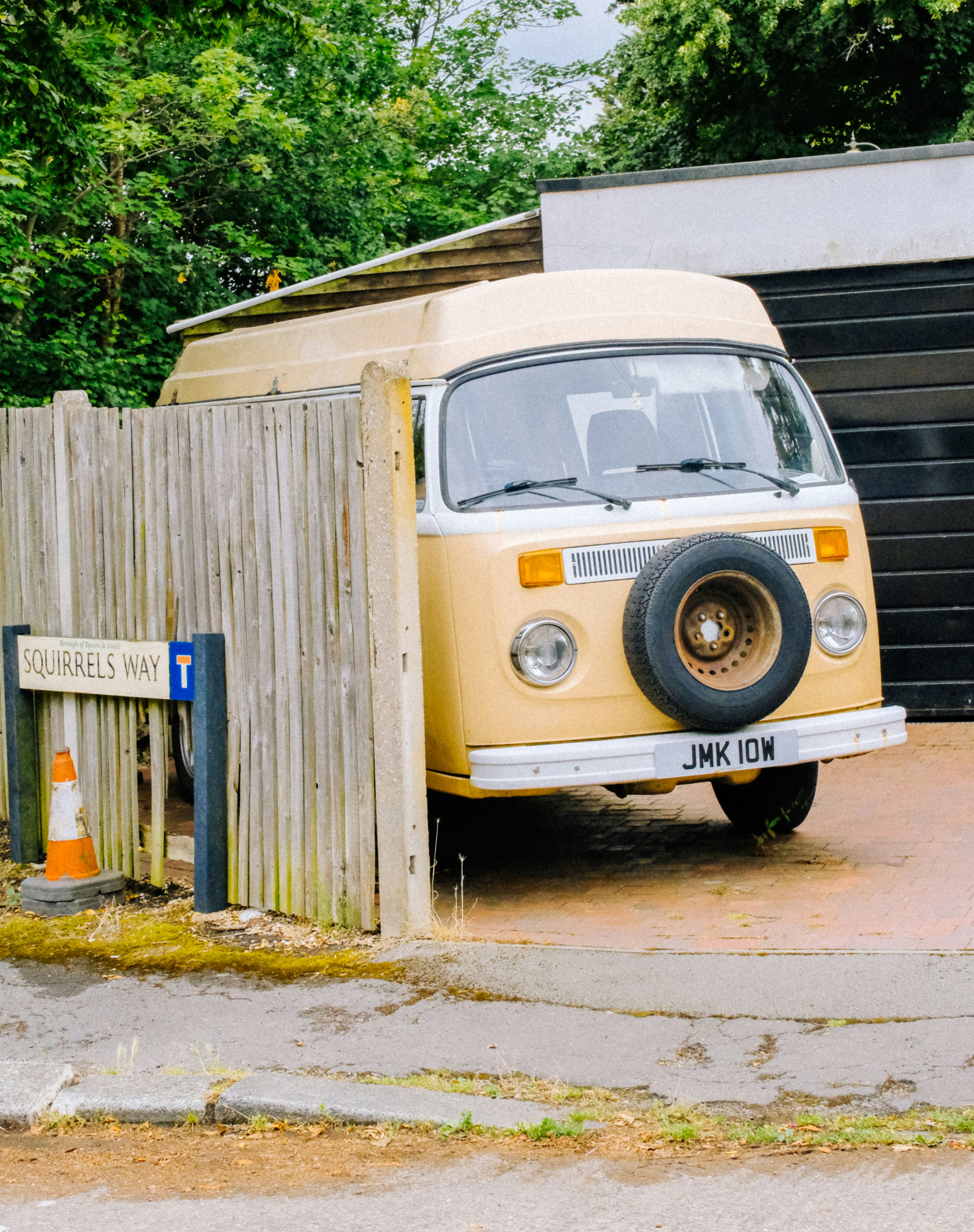 A yellow and white van parked in front of a garage