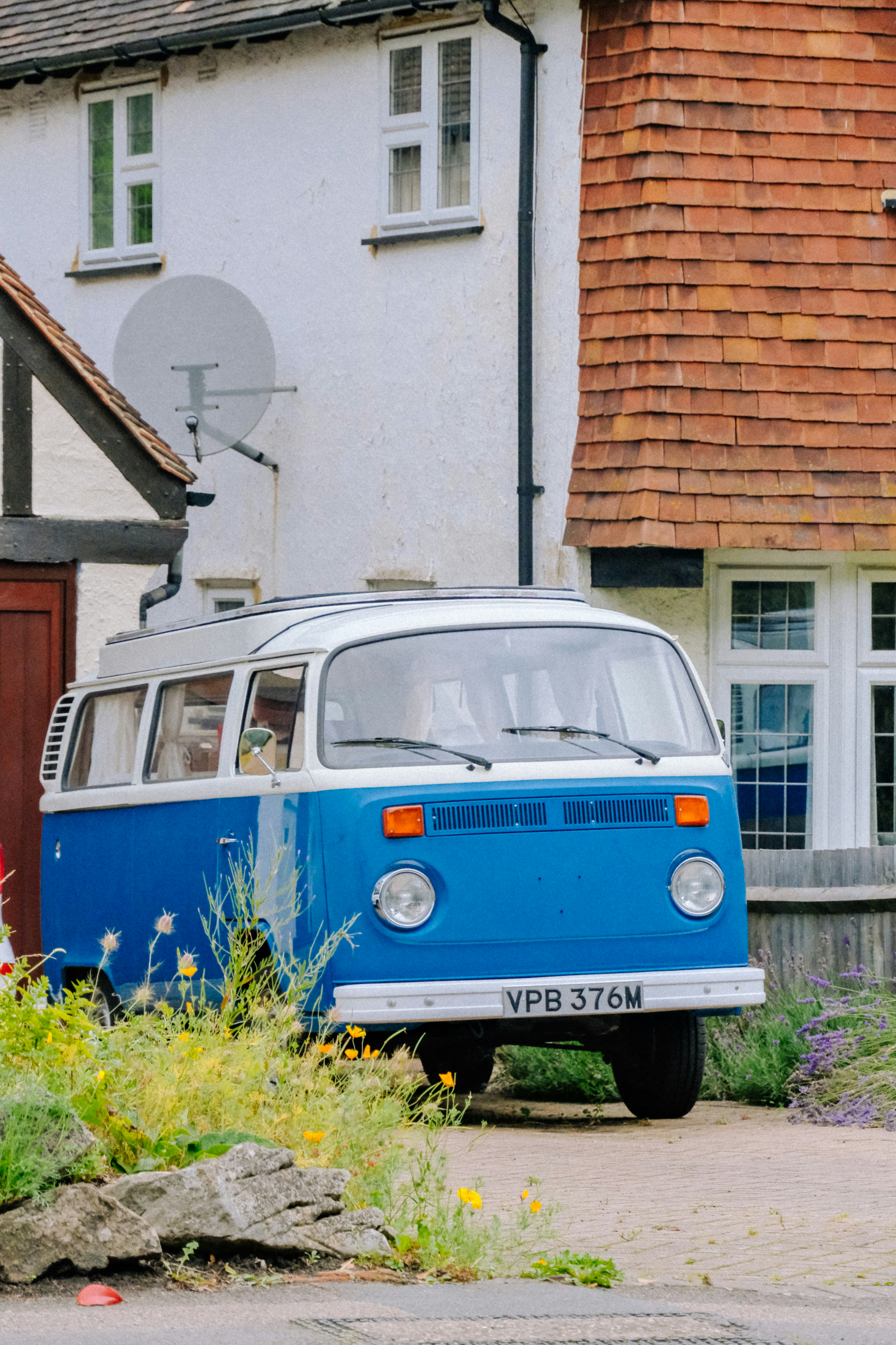 A blue and white van parked in front of a house